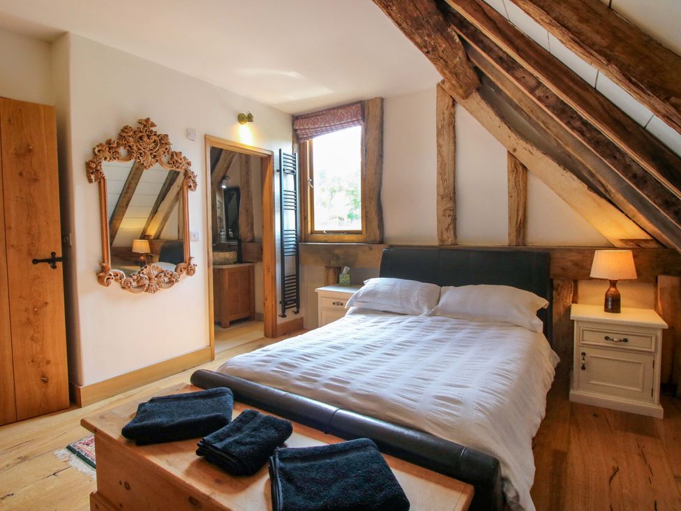 A bedroom with a bed and a mirror at Crook Barn Tenbury Wells