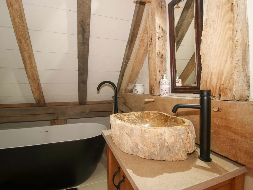 A bathroom with a bathtub and wooden sink at Crook Barn Tenbury Wells