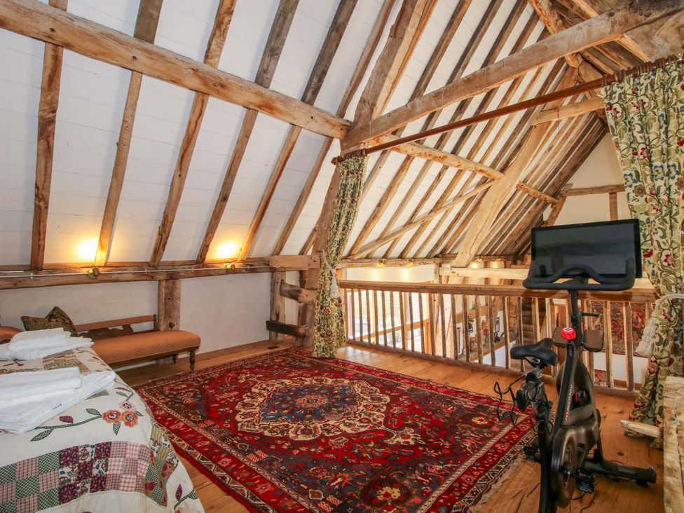 A loft with a rug, exercise bike, and sofa at Crook Barn Tenbury Wells