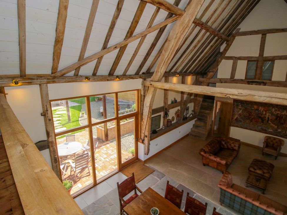 A living room with a staircase and dining table at Crook Barn in Tenbury Wells