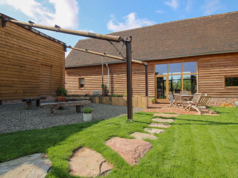A garden with a wooden building, gravel area, and dining furniture at Crook Barn in Tenbury Wells