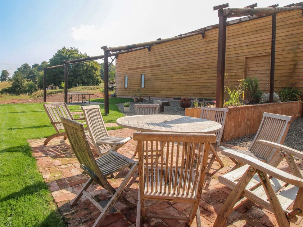 An outdoor seating area with a table and chairs at Crook Barn in Tenbury Wells