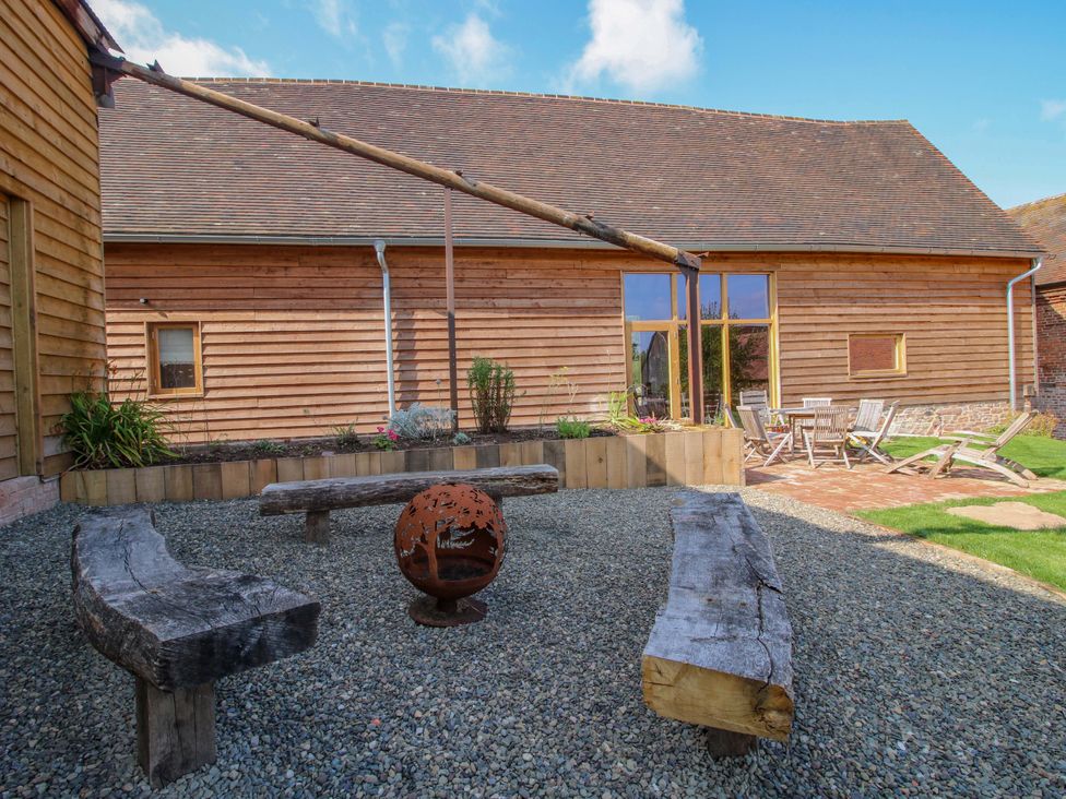 A garden with wooden benches and a fire pit at Crook Barn Tenbury Wells