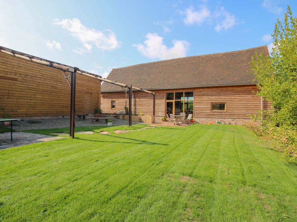 A garden with a wooden building and patio at Crook Barn Tenbury Wells