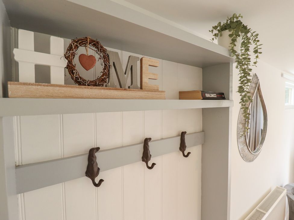 An entryway with a shelf, hooks, and a mirror at Pear Tree Lodge in Alford