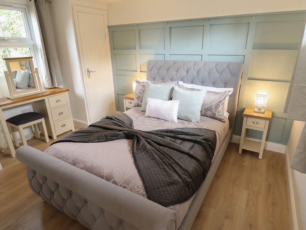 A bedroom with a bed and dressing table at Pear Tree Lodge in Alford