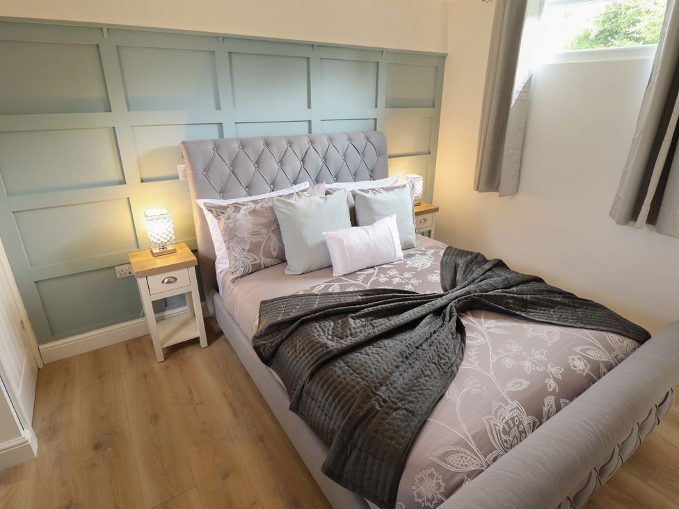 A bedroom with a bed and nightstand at Pear Tree Lodge in Alford
