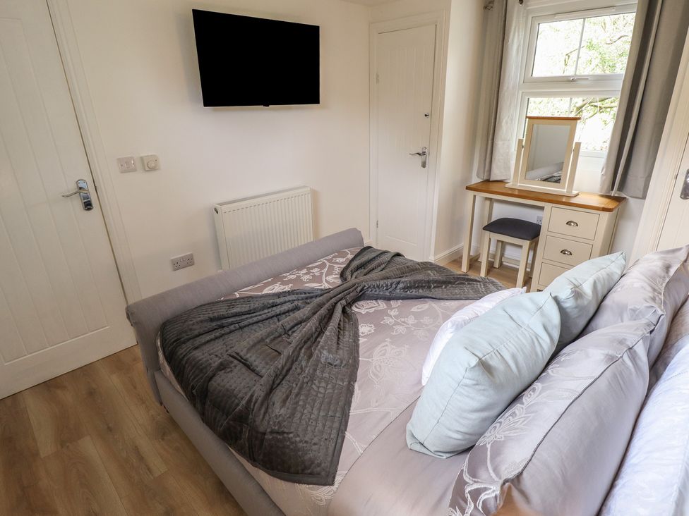 A bedroom with a bed, television, desk and chair at Pear Tree Lodge in Alford