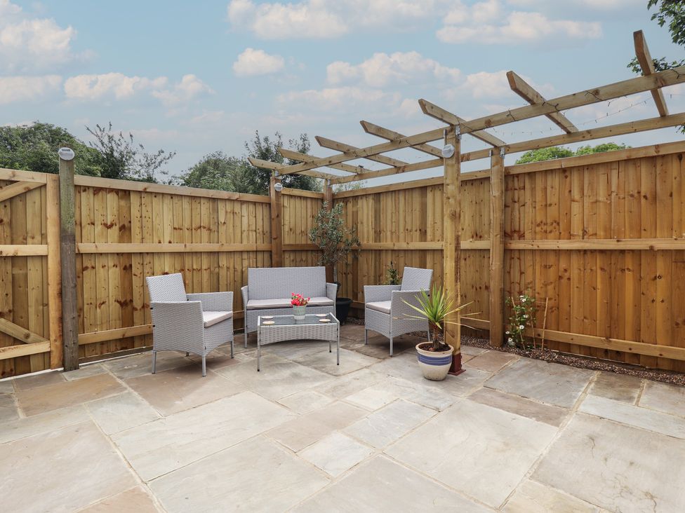 A garden with seating area and flower pot at Pear Tree Lodge in Alford