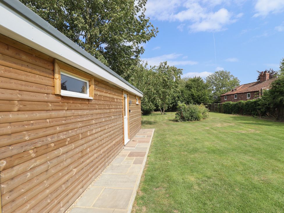 A wooden building exterior with a pathway in the garden at Pear Tree Lodge in Alford