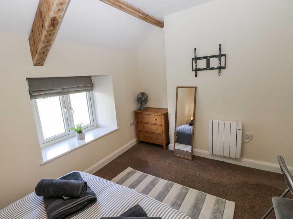 A bedroom with a window, plant, fan, and chest of drawers at Vern Dale in Builth Wells