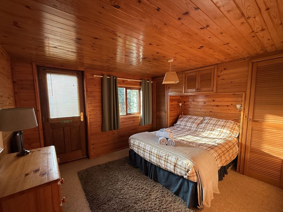 A bedroom with wooden walls and a bed at Oak Lodge in Mynydd Cerrig near Porthyrhyd