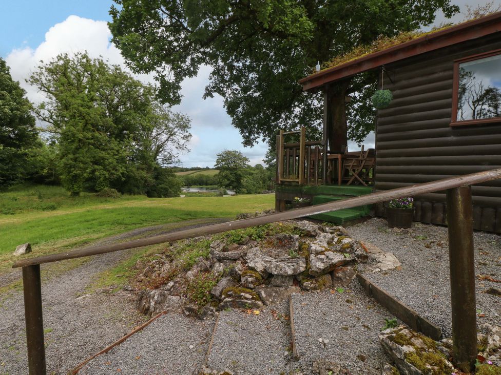 An outdoor view of a cabin with a deck and gravel path at Oak Lodge in Mynydd Cerrig near Porthyrhyd
