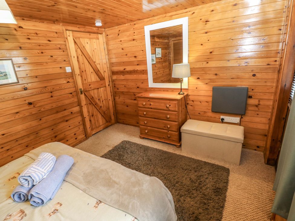 A bedroom with a bed and dressing table at Oak Lodge in Mynydd Cerrig near Porthyrhyd
