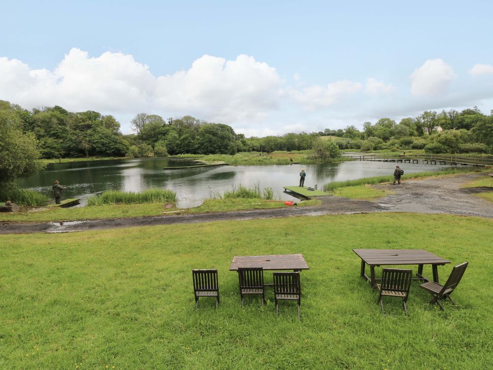 An outdoor area with a lake and fishing activity at Oak Lodge near Mynydd Cerrig