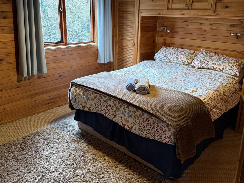 A bedroom with a bed and window at Ash Lodge in Mynydd Cerrig near Porthyrhyd