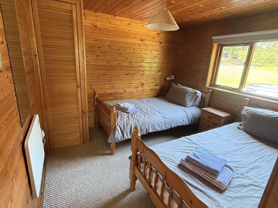 A bedroom with two twin beds and a nightstand at Ash Lodge near Mynydd Cerrig
