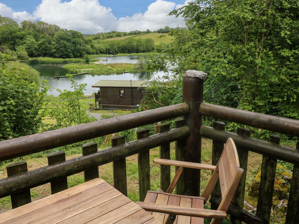 A view from a wooden balcony overlooking a lake at Ash Lodge in Mynydd Cerrig near Porthyrhyd