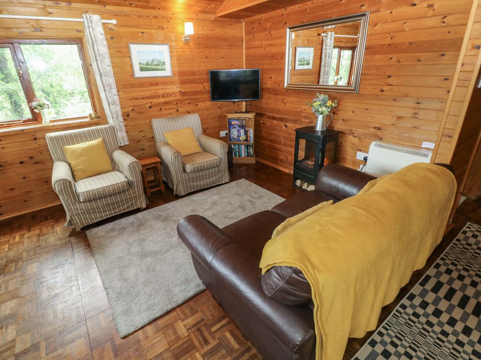 A living room with a sofa and armchair at Ash Lodge near Mynydd Cerrig