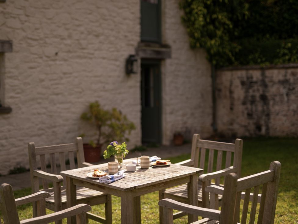 A garden with a wooden table and chairs at West Cottage in Llandovery