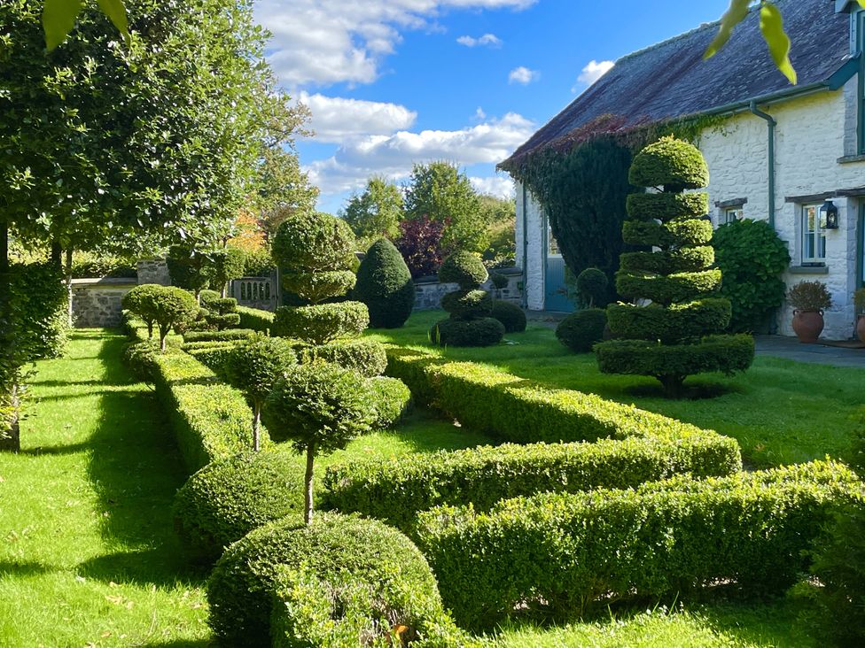 A garden with topiary and a house at West Cottage in Myddfai near Llandovery