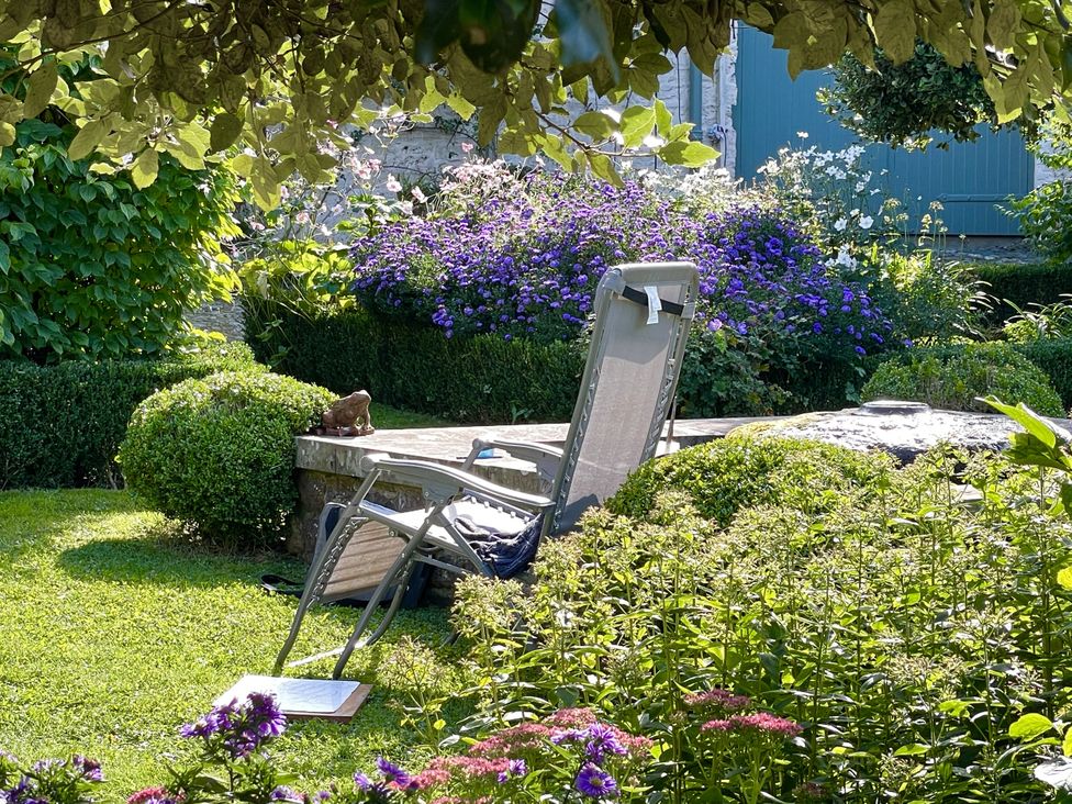 A garden with a lounge chair and flowers at West Cottage Myddfai near Llandovery