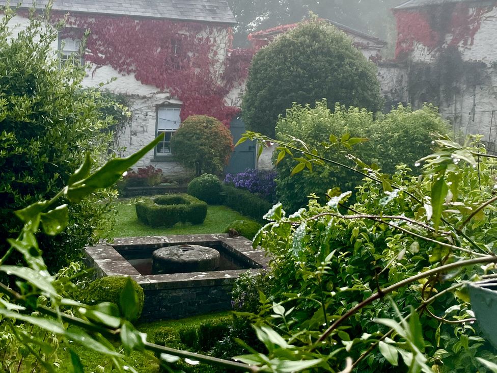A garden with a fountain and bushes at West Cottage in Myddfai near Llandovery