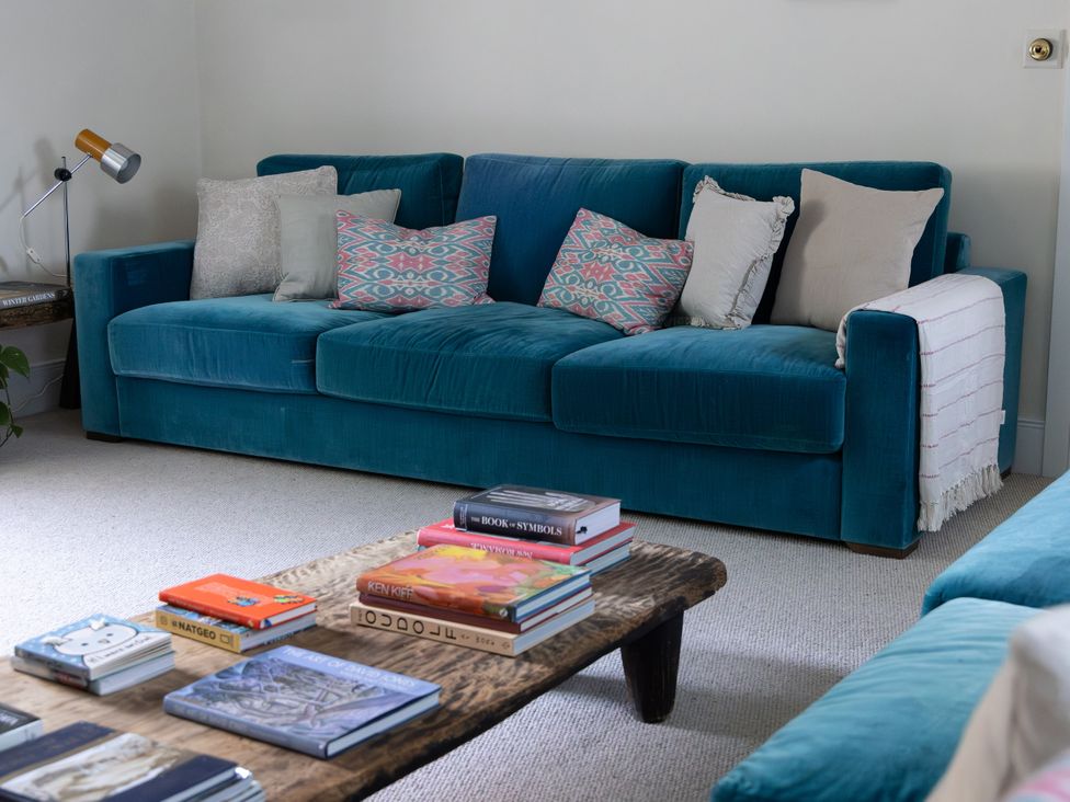 A living room with a sofa, coffee table and books at West Cottage in Myddfai near Llandovery