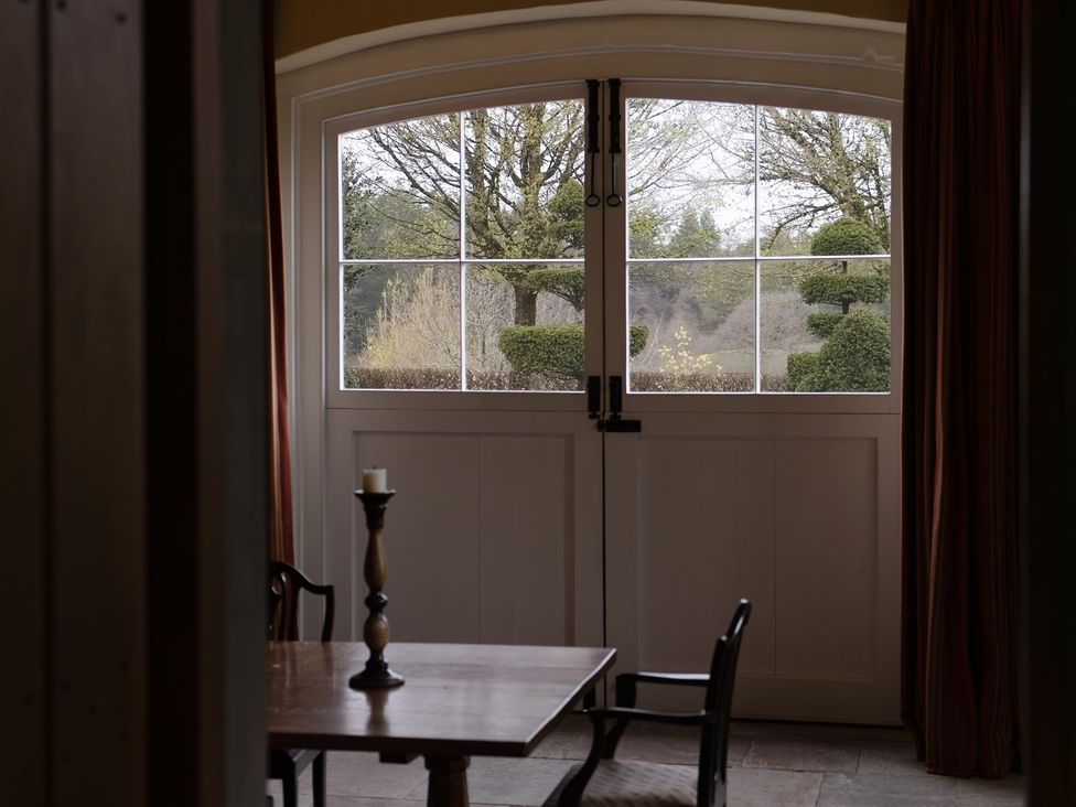 A window with a view of a garden and a table with a candle at West Cottage Myddfai near Llandovery