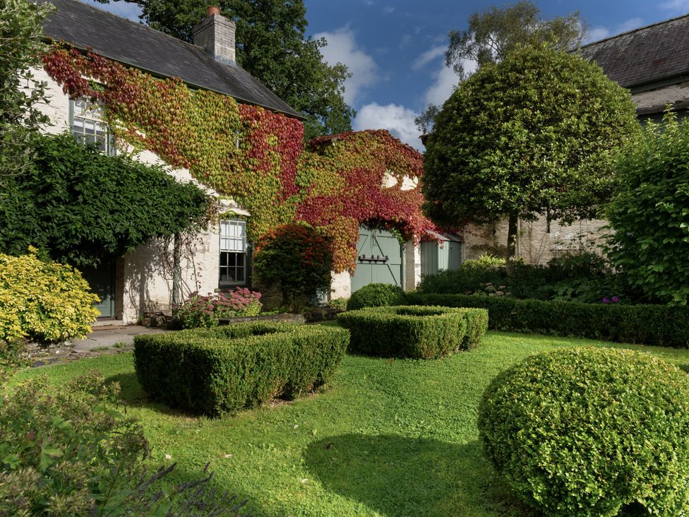 A garden with hedges and trees at Gatekeepers Cottage in Llandovery