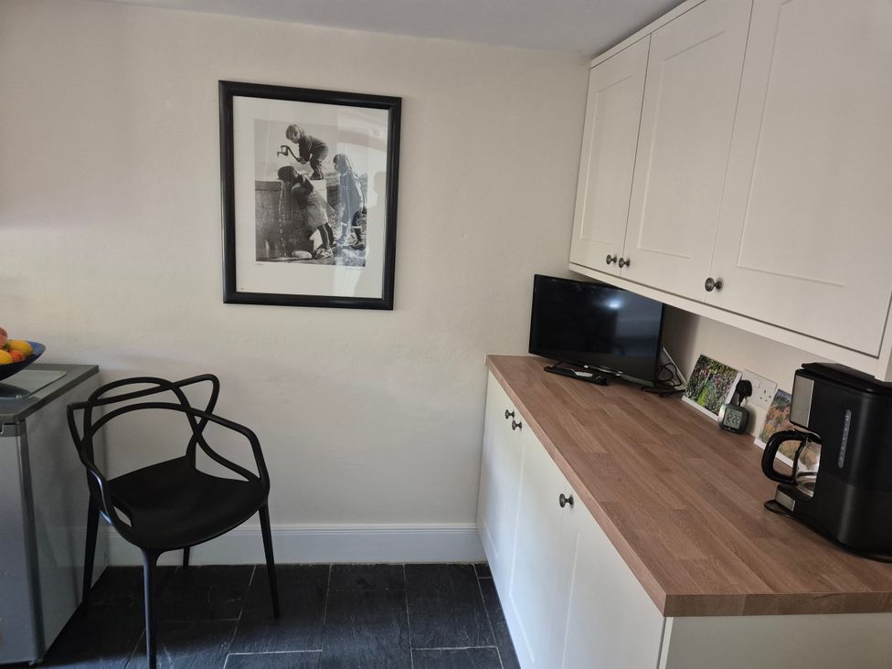 A kitchen with a chair, television and kettle at Gatekeepers Cottage near Llandovery