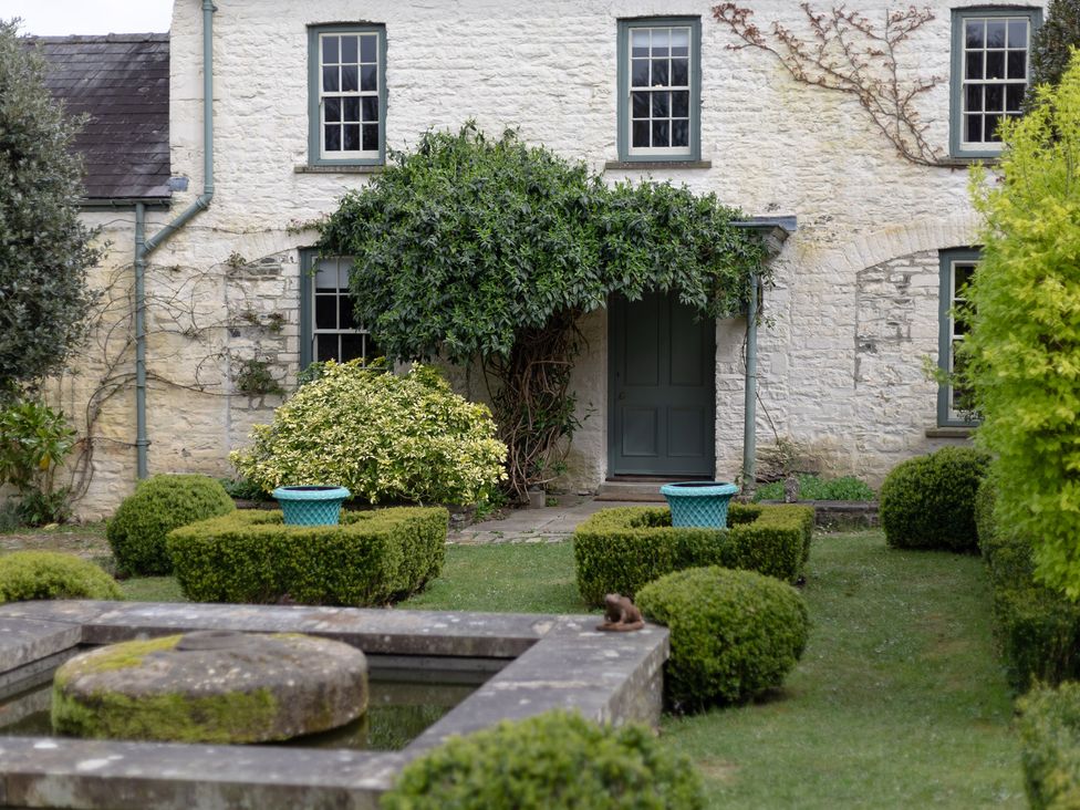 An outdoor area with a bush and a stone fountain at Gatekeepers Cottage, Myddfai near Llandovery