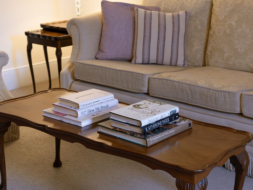 A living room with a sofa and coffee table stacked with books at Gatekeepers Cottage Myddfai near Llandovery