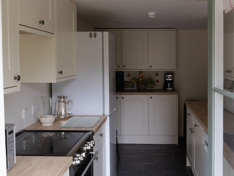 A kitchen with cabinets, cooking range, refrigerator and coffee maker at Gatekeepers Cottage, Myddfai near Llandovery