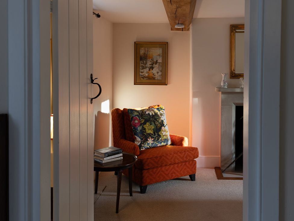 A snug featuring an armchair, table with books and a fireplace at Gatekeepers Cottage near Llandovery