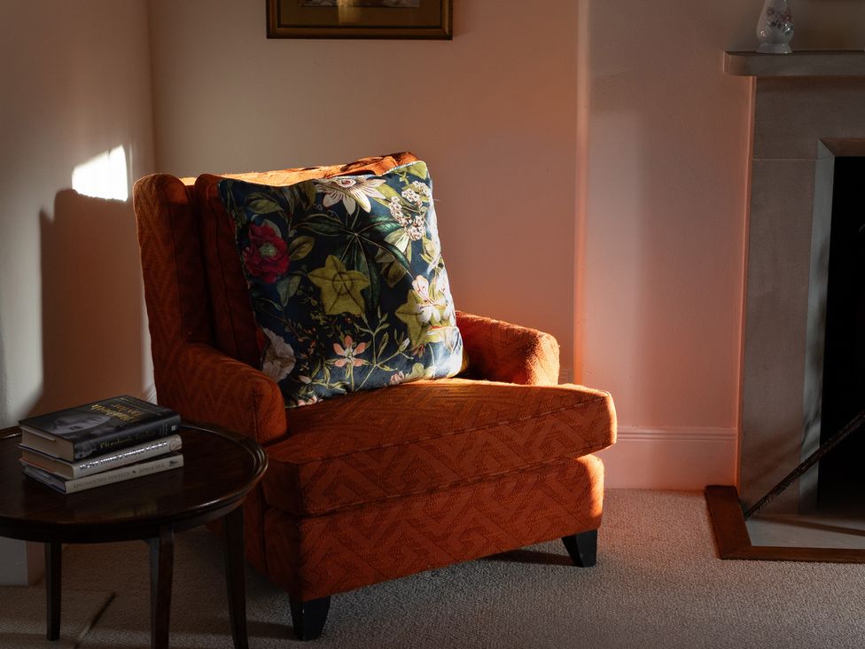 A living room with an armchair and a table with books at Gatekeepers Cottage Myddfai near Llandovery