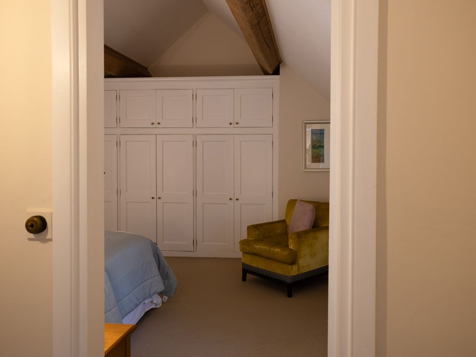 A bedroom with a bed and an armchair at Gatekeepers Cottage in Myddfai near Llandovery