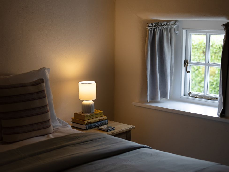 A bedroom with a bed and a lamp on a bedside table at Gatekeepers Cottage in Myddfai near Llandovery