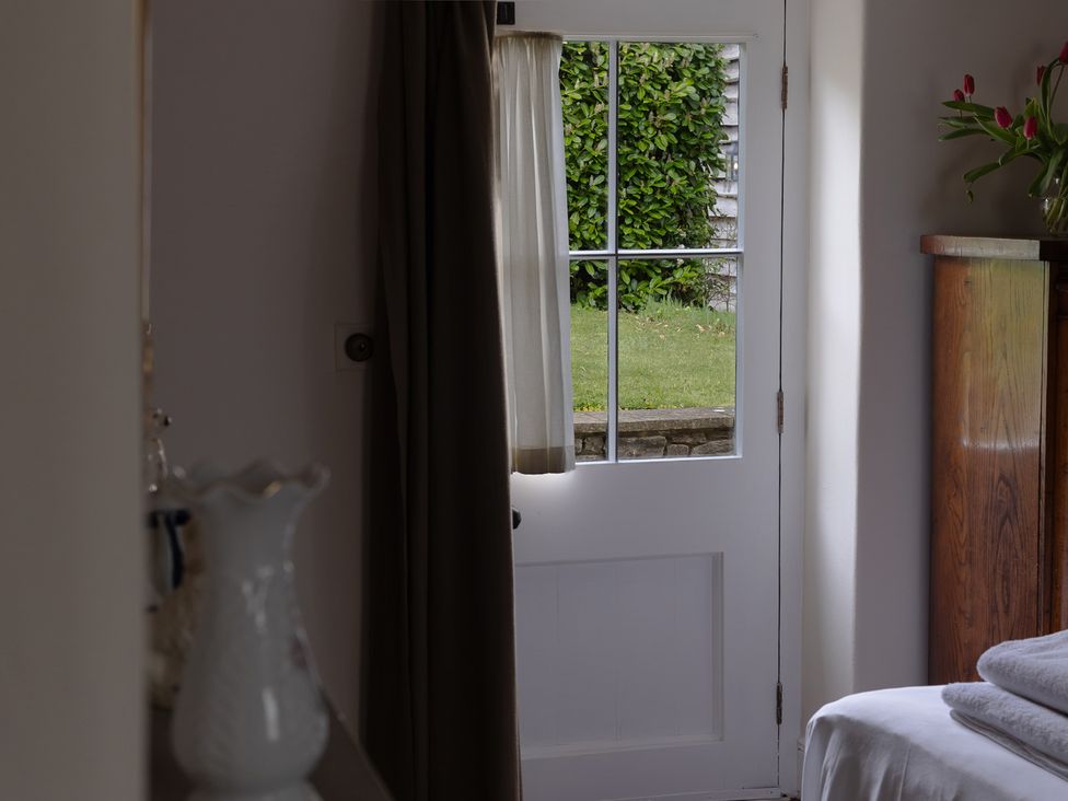 A door with a window and curtain in a bedroom at Gatekeepers Cottage Myddfai near Llandovery