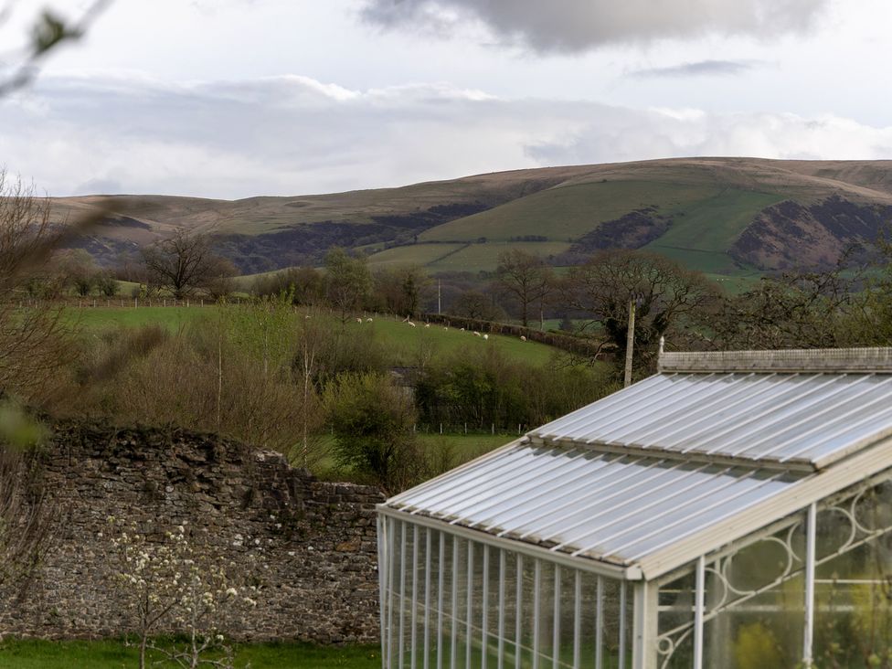 A greenhouse and hills in the background at Gatekeepers Cottage in Myddfai near Llandovery