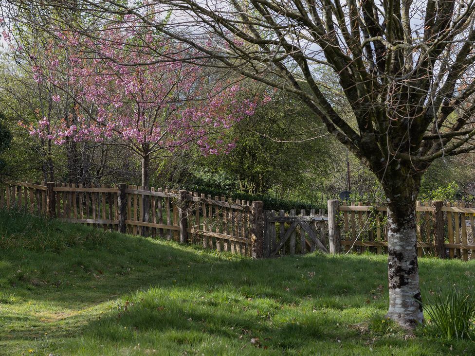 A garden with a fence and flowering tree at Gatekeepers Cottage in Myddfai near Llandovery