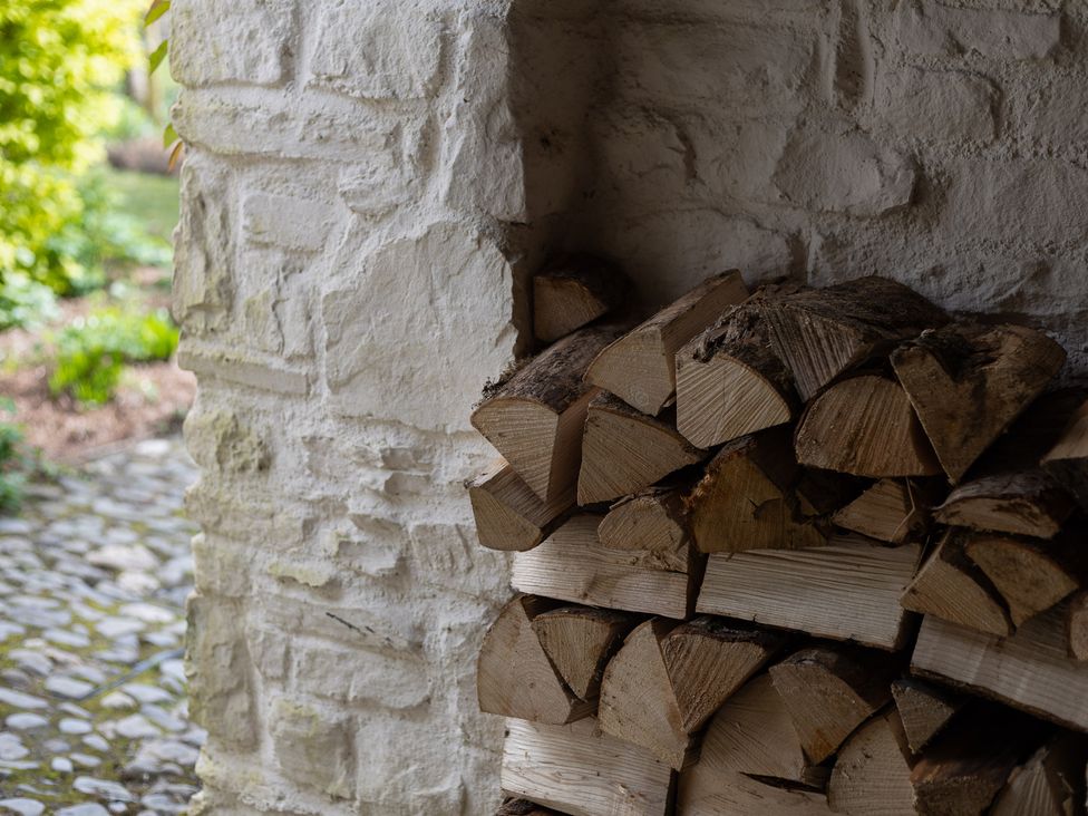 A stack of firewood beside a stone wall in the garden at Gatekeepers Cottage Myddfai near Llandovery