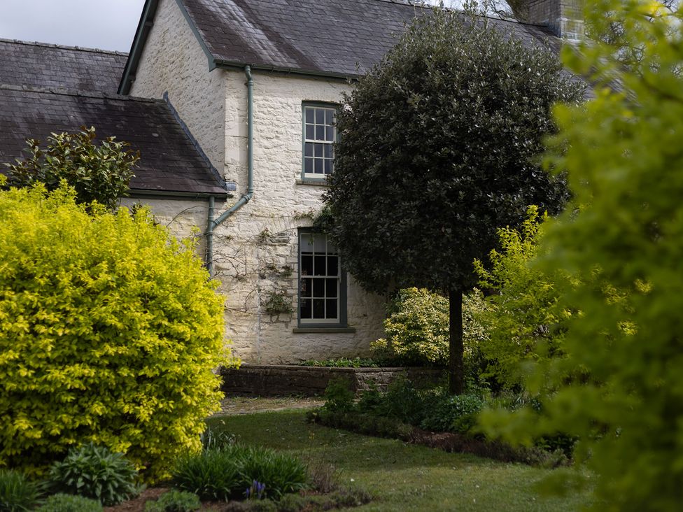 A house with a tree and bushes at Gatekeepers Cottage in Myddfai near Llandovery