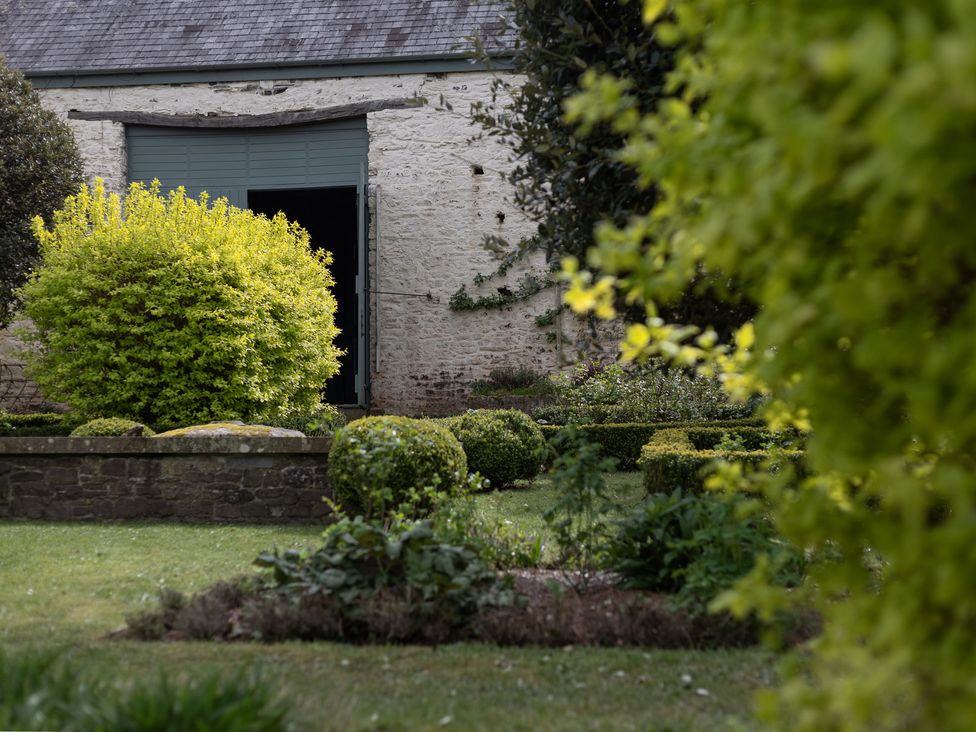 A garden with bushes and a building entrance at Gatekeepers Cottage in Myddfai near Llandovery