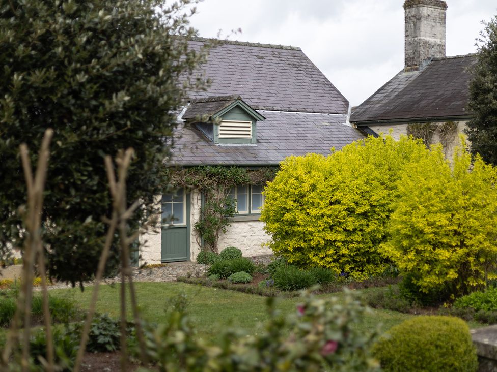 A cottage with a green door and a yellow bush at Gatekeepers Cottage in Myddfai near Llandovery