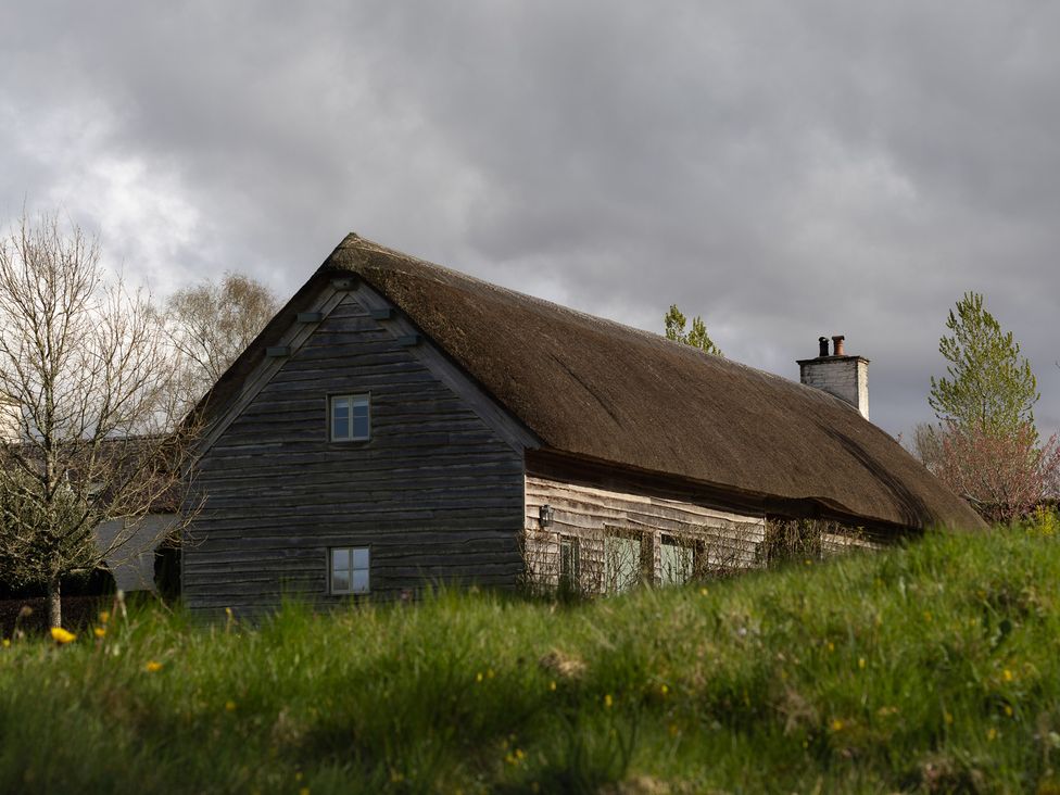 A house with a thatched roof and windows at Gatekeepers Cottage in Myddfai near Llandovery