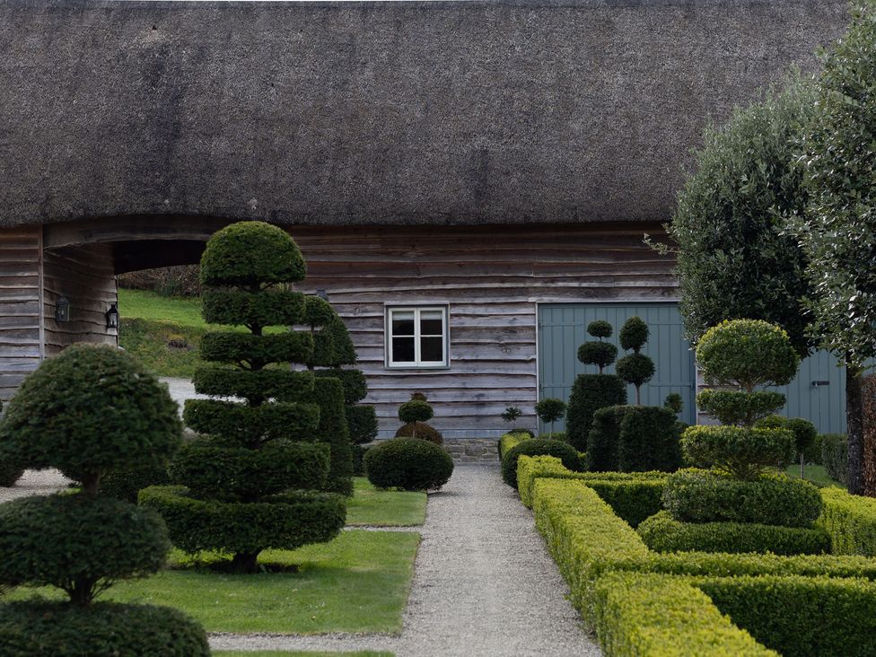 A garden with topiary shrubs and a wooden building at Gatekeepers Cottage in Myddfai near Llandovery