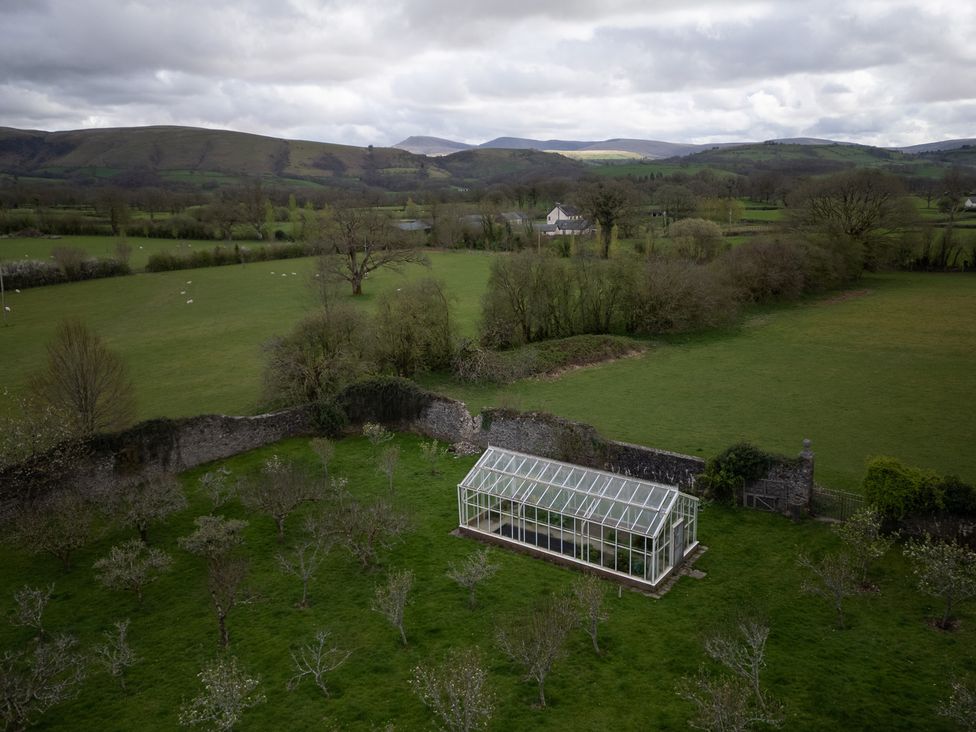 A greenhouse surrounded by grass and trees at Gatekeepers Cottage Myddfai near Llandovery