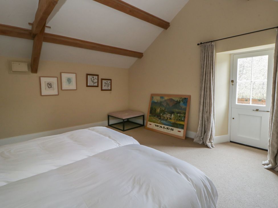 A bedroom with two beds and a door at North Cottage in Llandovery