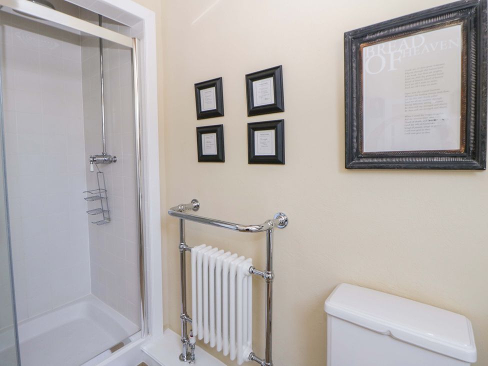A bathroom with a shower, towel radiator, and framed artwork at North Cottage Myddfai near Llandovery